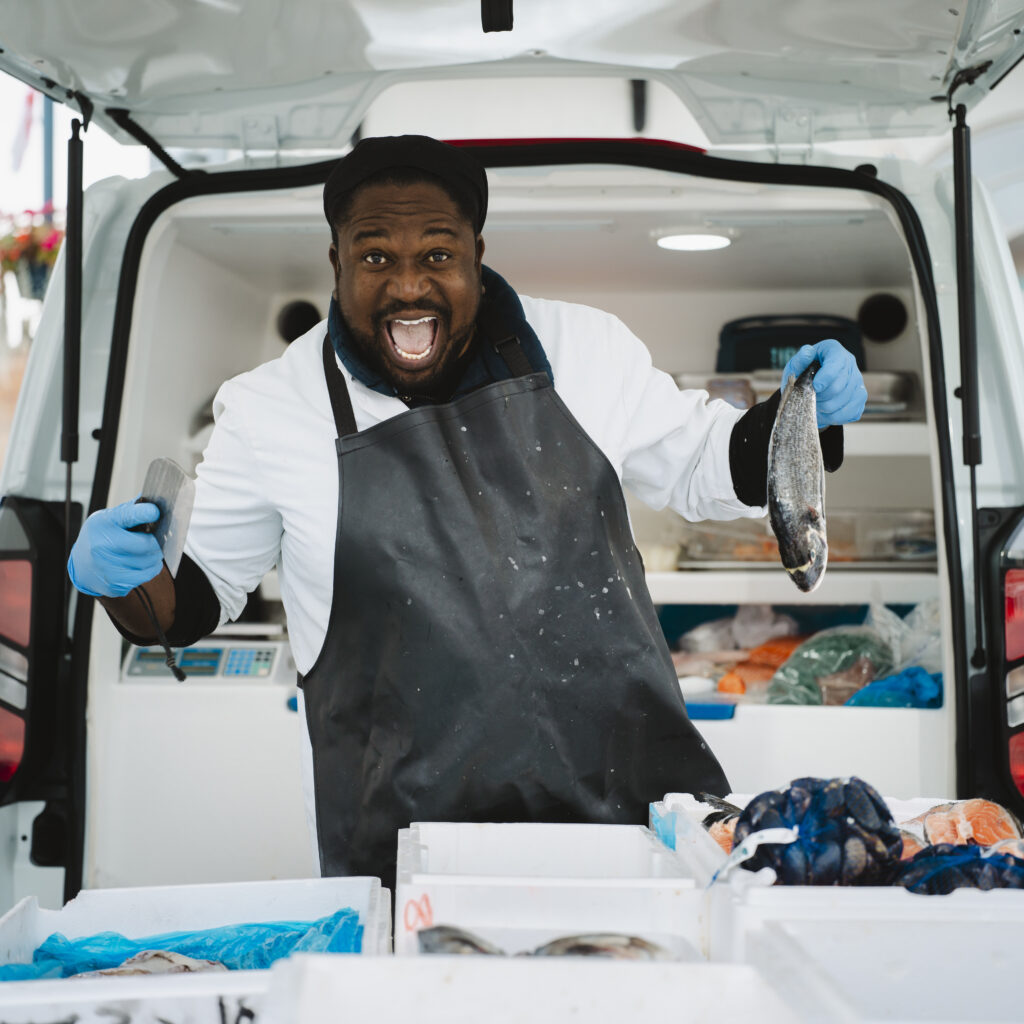 Portrait by Steven Hatton of a Boston fishmonger holding fresh fish at a market stall, part of The Bostonians exhibition