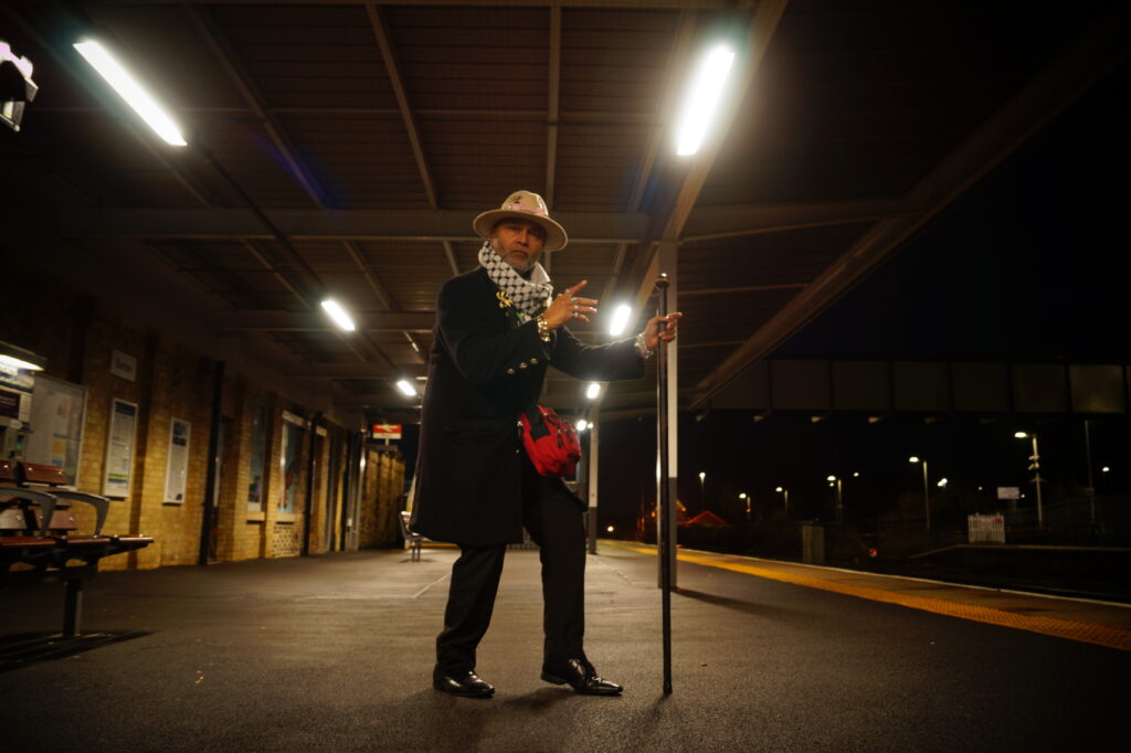 Portrait by Bartosz Fedkowicz of a figure standing on a Boston train station platform at night, part of Kaleidoscope exhibition