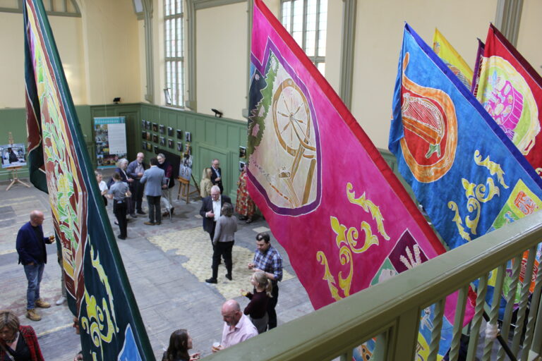 Colourful silk-painted heritage themed banners hang from the balcony of the Great Hall in Shodfriars, Boston