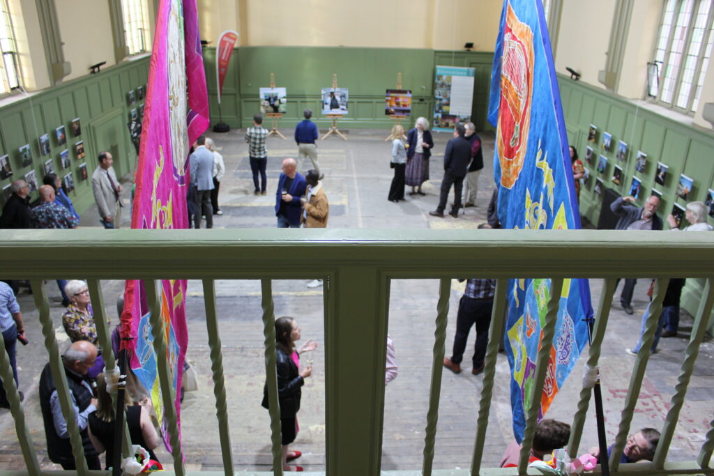 Visitors viewing The Bostonians exhibition at Shodfriars Hall, Boston, featuring community portraits and artwork displays