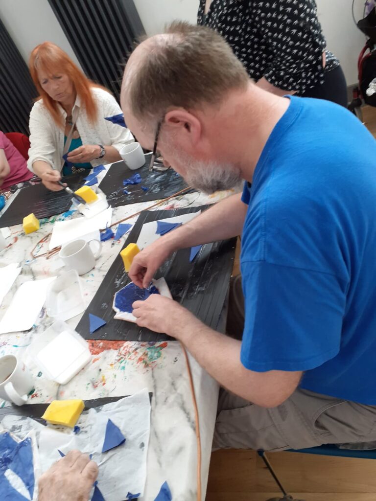 Centrepoint Outreach participants creating skullcap flowers for costumes during an art workshop using painted papers and craft tools
