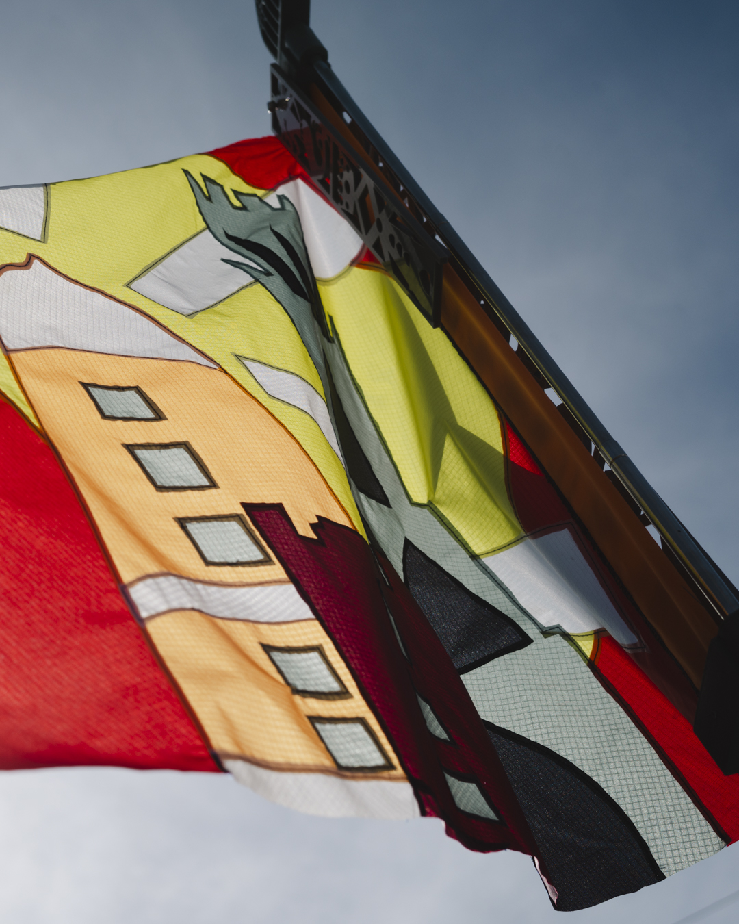 Colourful Swineshead Pageant flag featuring illustrated buildings on the design, displayed outdoors for Transported arts exhibition in Boston, Lincolnshire