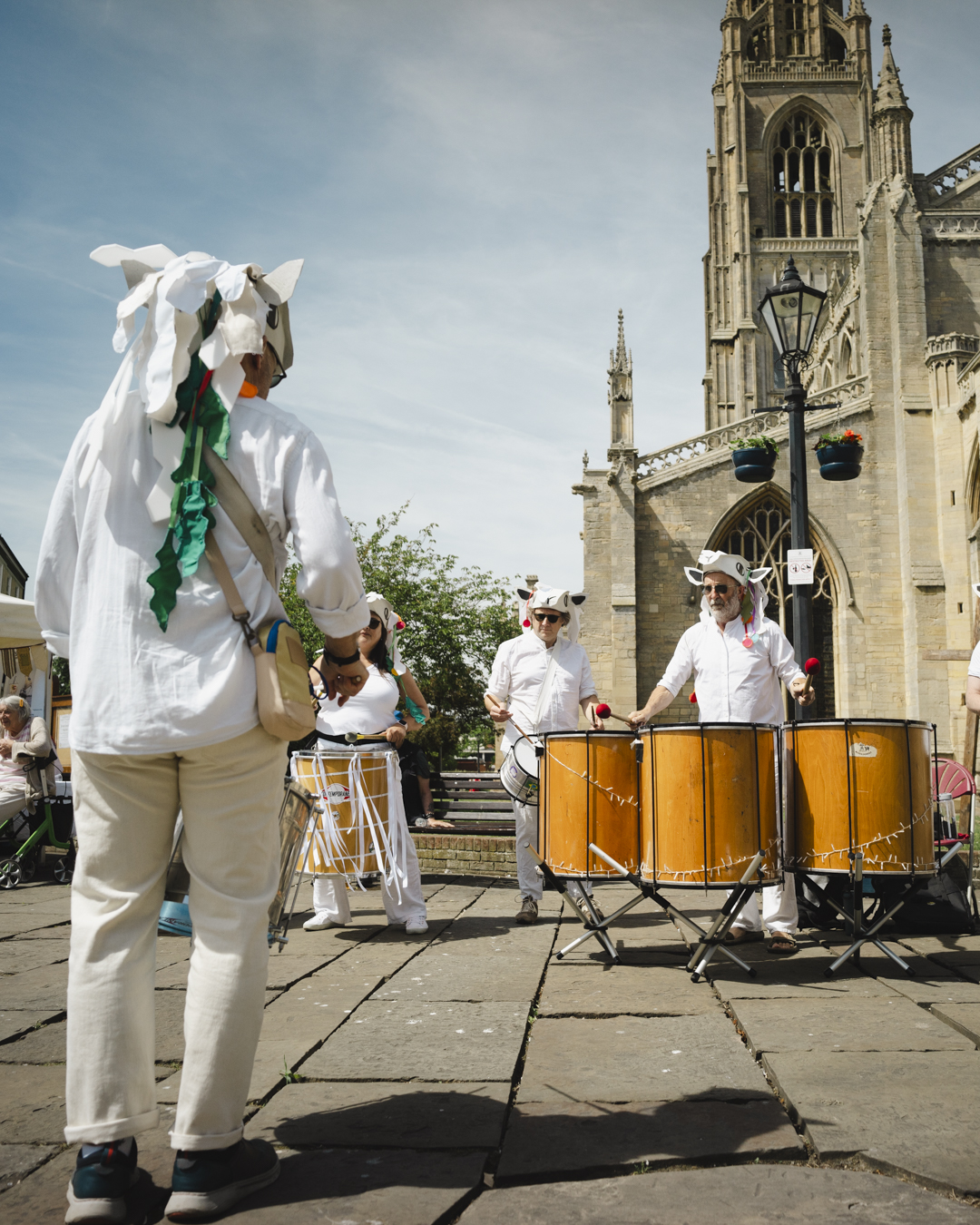 Drummers performing outdoors near St Botolph’s Church in Boston with large drums during a daytime community event