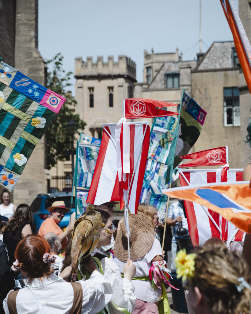 Boston Hanseatic Day parade with participants wearing Hansekoggen boat costumes and carrying red and white ship sails through the town centre