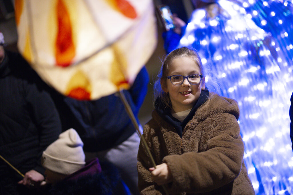 Participant carrying an illuminated lantern during the Illuminate winter lantern parade in Boston town centre.