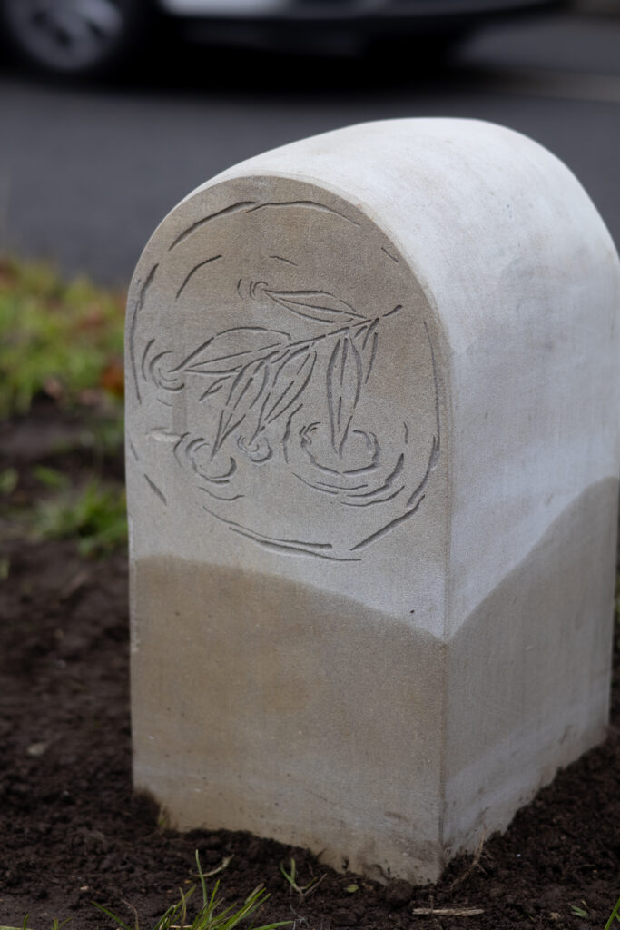 A small stone way maker with an engraved illustration of leaves, part of the Spalding Riverside Trail