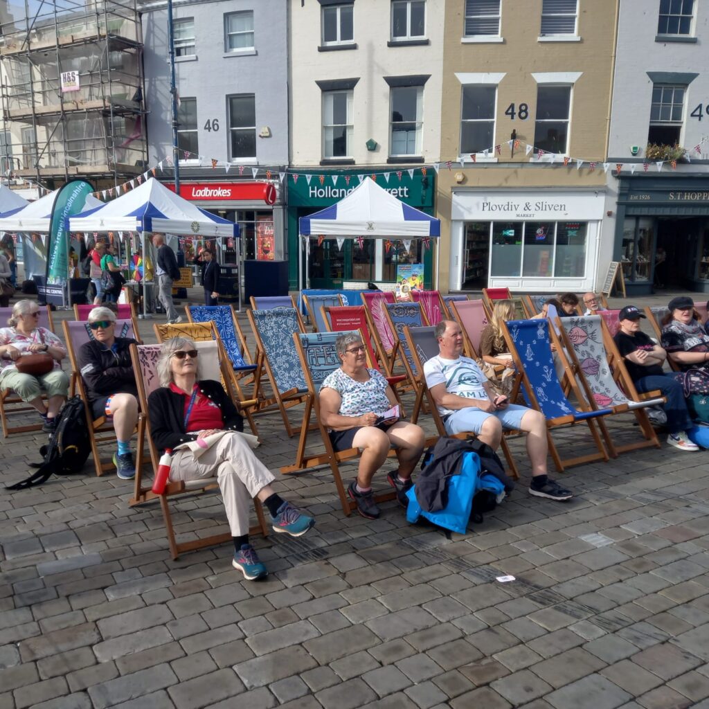 Crowds sit on colourful Transported deckchairs to watch the live video footage screening of the Tour of Britain race in Boston Market Square