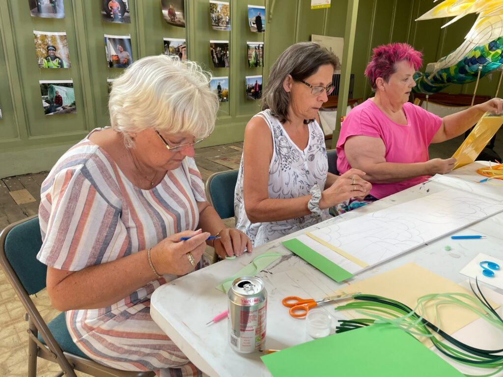 Participants creating colourful flag designs with marker pens and rolled paper in a method called quilling
