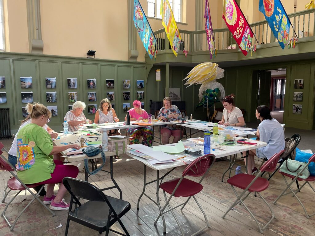 Participants creating colourful flag designs with marker pens and rolled paper in a method called quilling