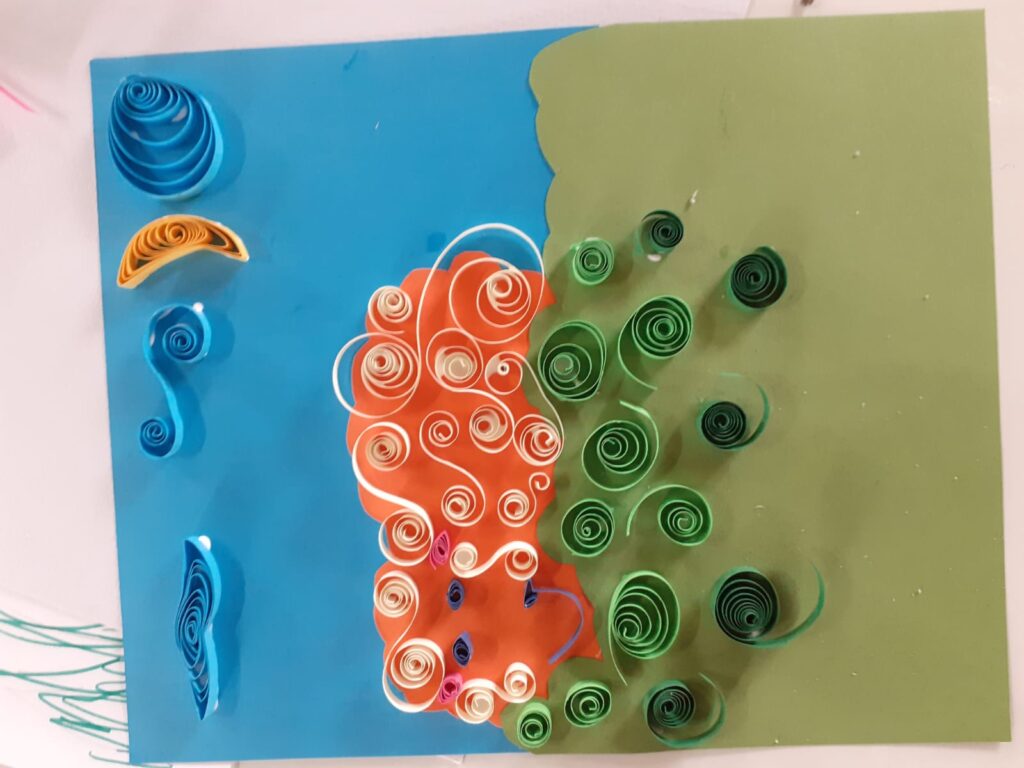 Participants creating colourful flag designs with marker pens and rolled paper in a method called quilling