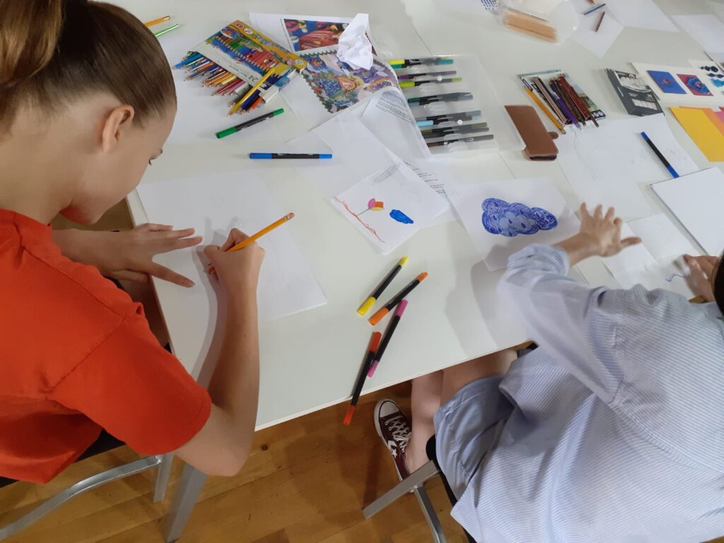 Participants creating colourful flag designs with marker pens and rolled paper in a method called quilling
