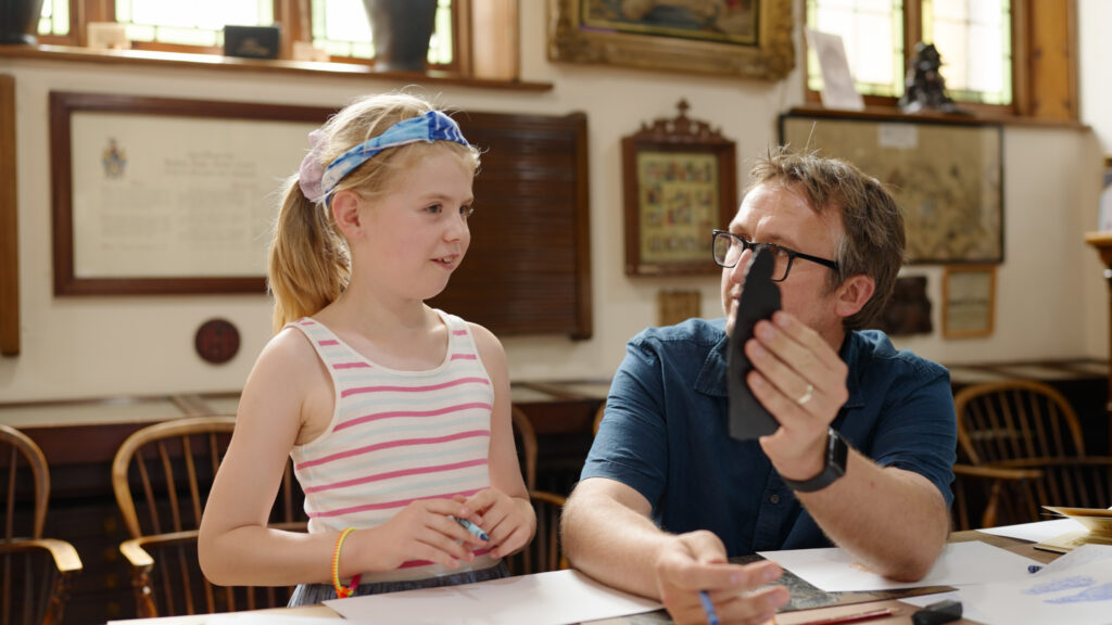 Artist Steven Hatton explores an Spalding Gentlemen Society Museum's artefact with a young visitor