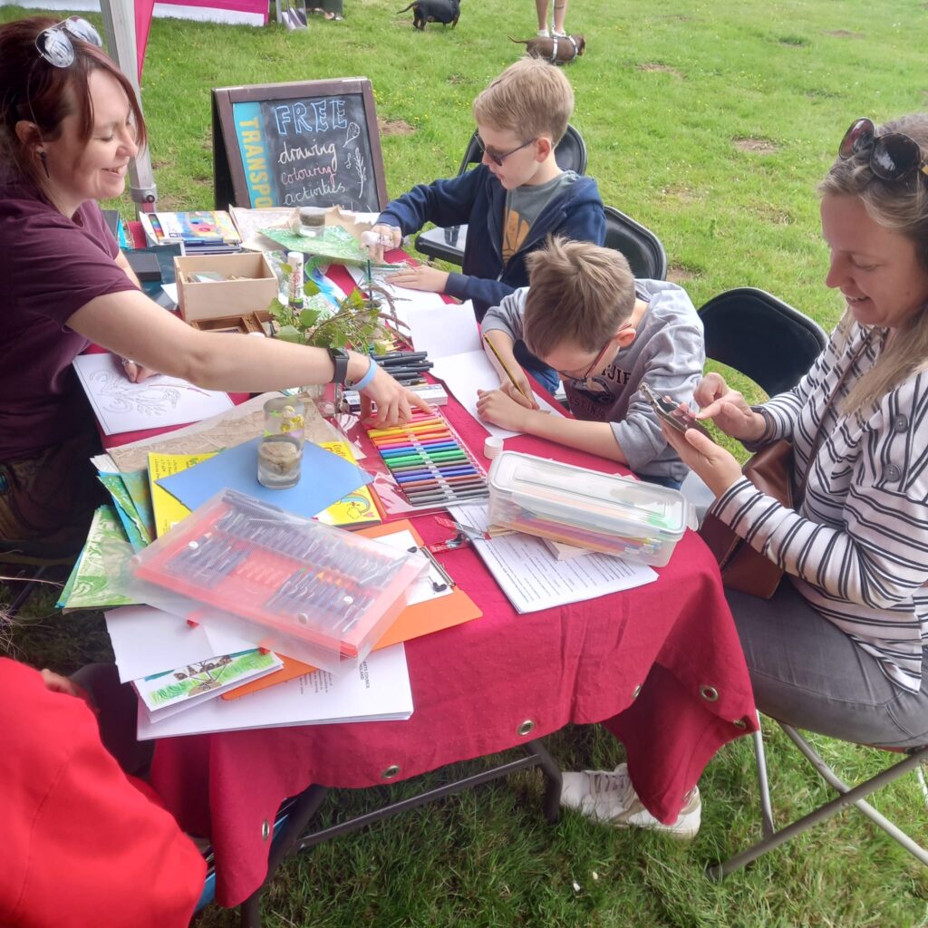 Artist Emily Cartwright leading a family in a sketching activity at an outdoor event