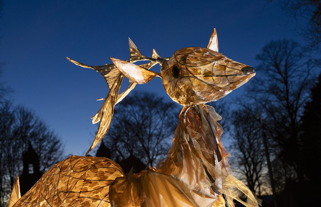 A large illuminated stag lantern glows against a dusk sky