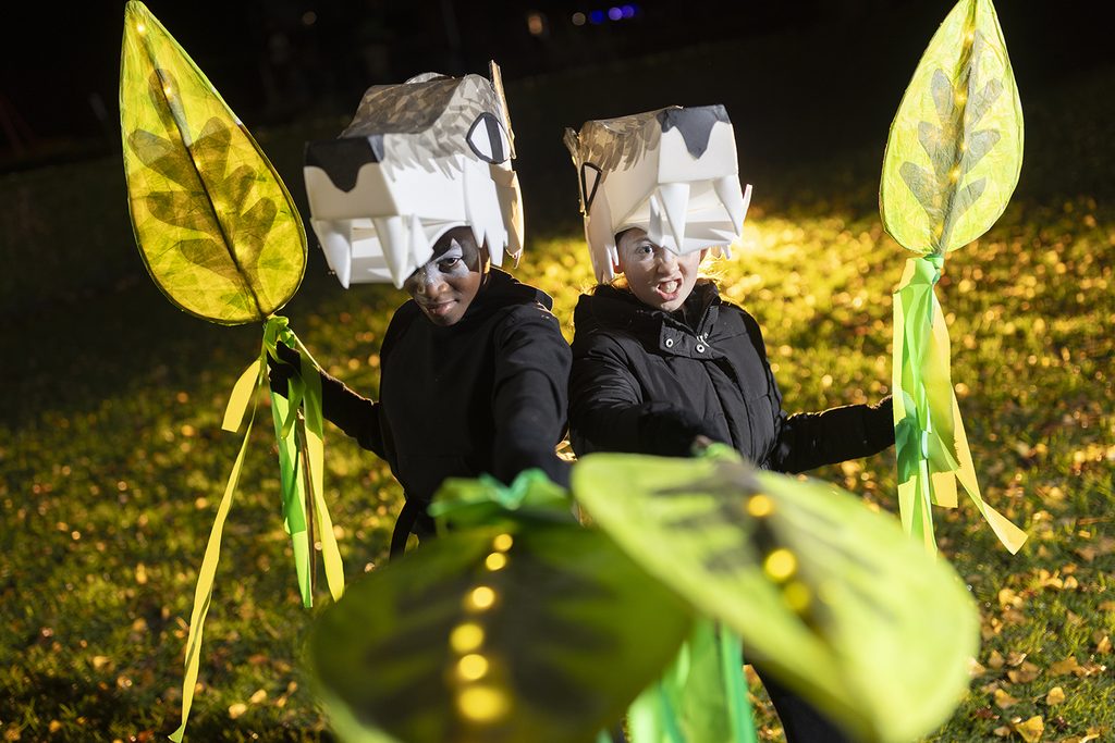Two costumed dancers wearing wolf masks growl at the camera