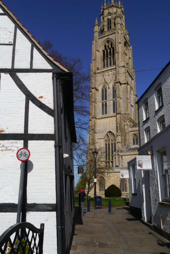 Wide shot of the side of wobbly historic Tudor house, Church House with St Botolphs seen beyond in Boston