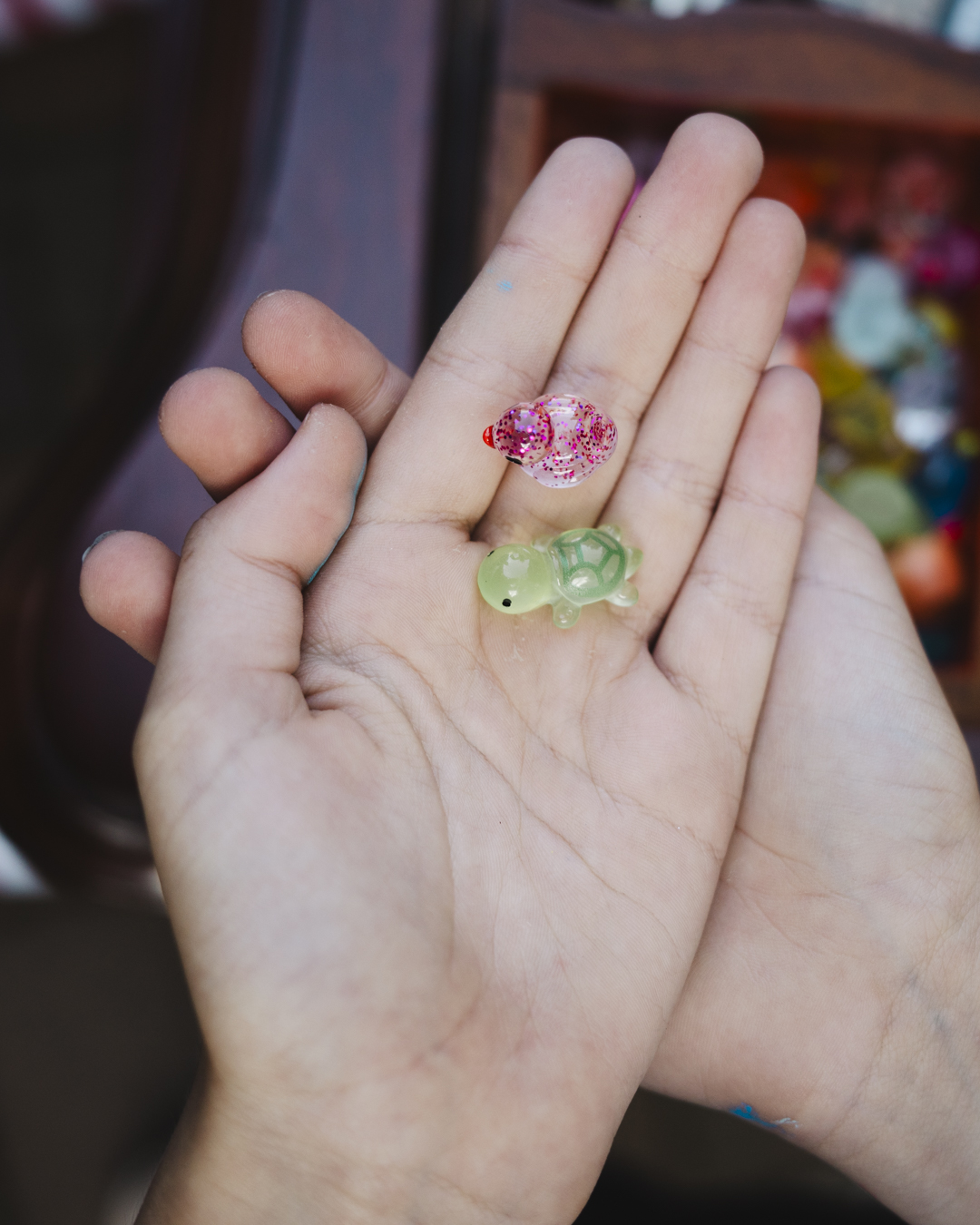 A close image a hands outspread holding small plastic duck and turtle toys, curious items found in the Cabinet of Curiosities