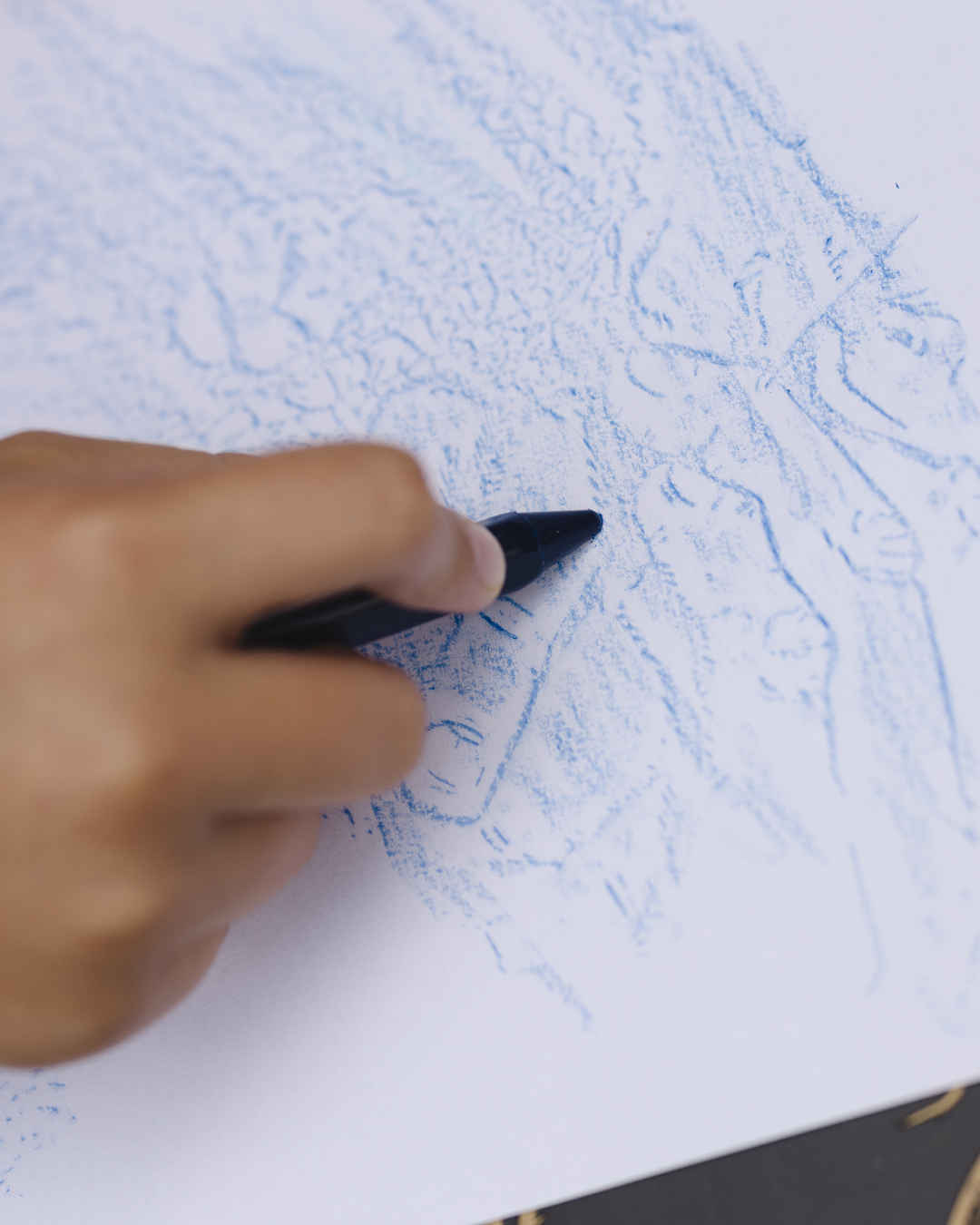 Close up image of a child's hand using a crayon to create a brass rubbing image