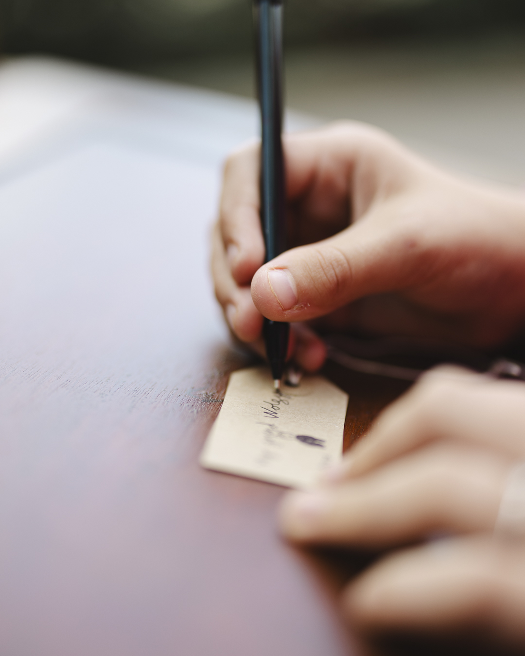 A close up image of someone writing onto a brown kraft label, writing what item of theirs they would preserve in a museum
